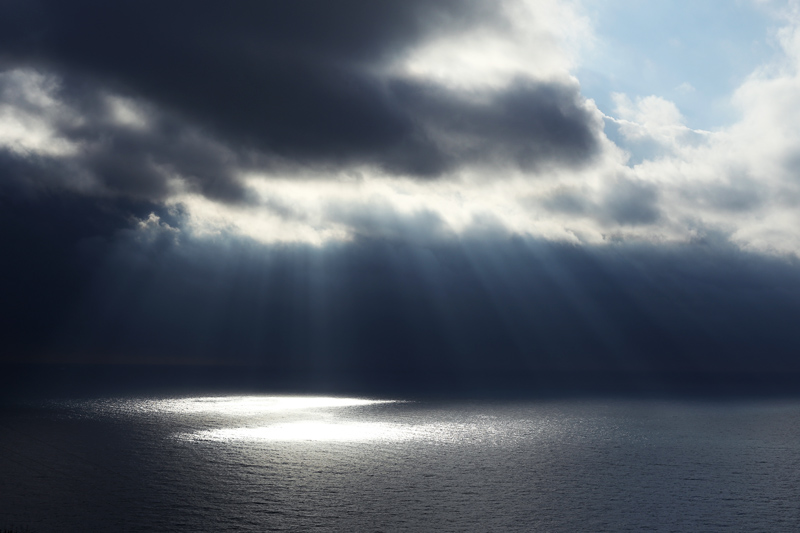 raggi di sole filtrano dalle nuvole sul mare