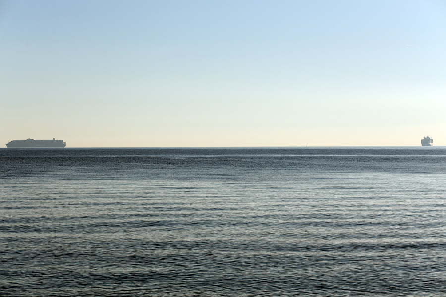 Two cargo ships on the horizon in a Mediterranean seascape under a clear sky