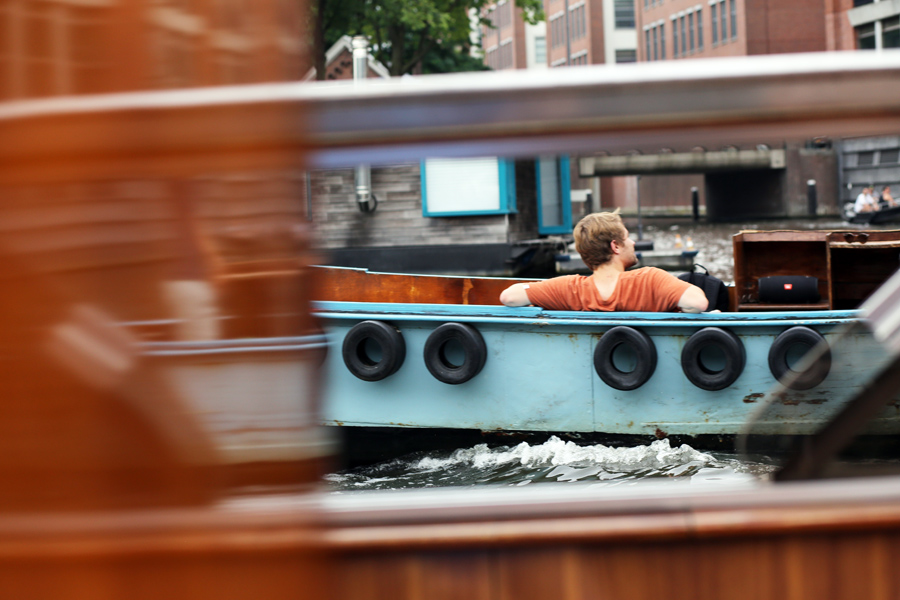 Peaceful boat ride through Amsterdam canals with people enjoying a relaxing moment on the water